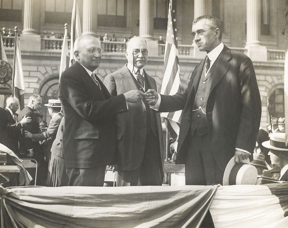 Cyrus Adler, the president of the Board of Trustees of the Free Library of Philadelphia (left), presents the keys to the Central Library of the Free Library of Philadelphia to Librarian John Ashhurst (right) as Clinton Rogers Woodruff
