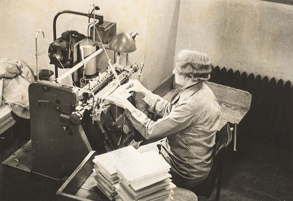 Bindery worker running an oversewing machine at the Central Library of the Free Library of Philadelphia