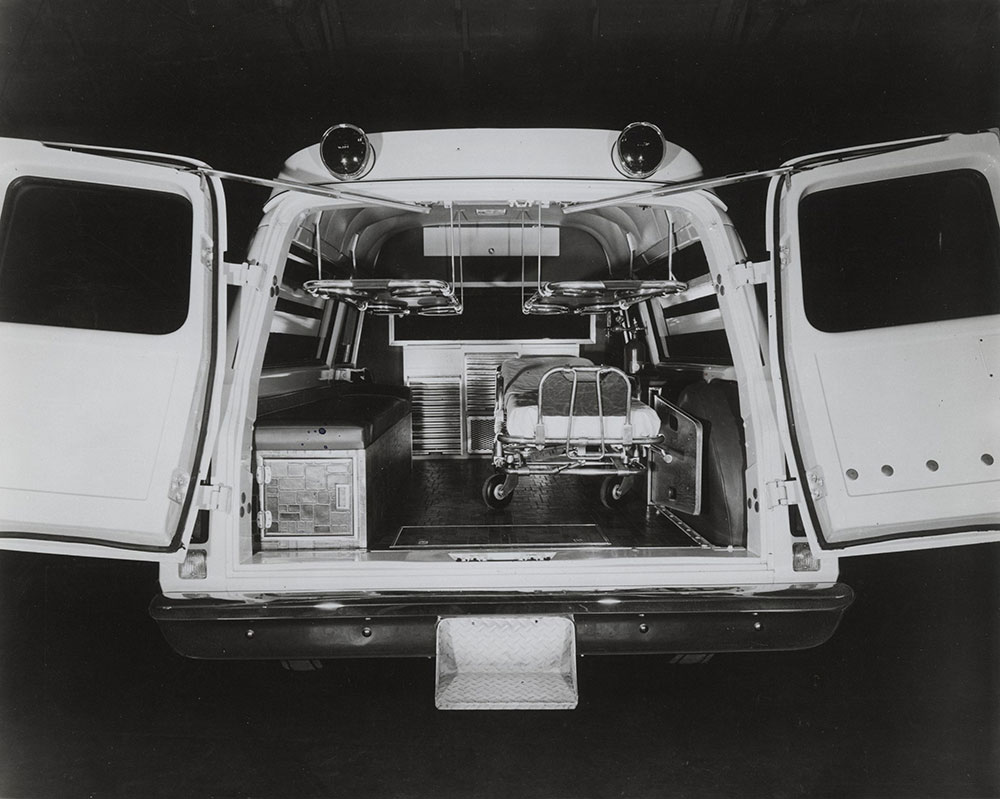 Ambulance: rear view, doors open, showing interior, with gurney. Make, date unknown