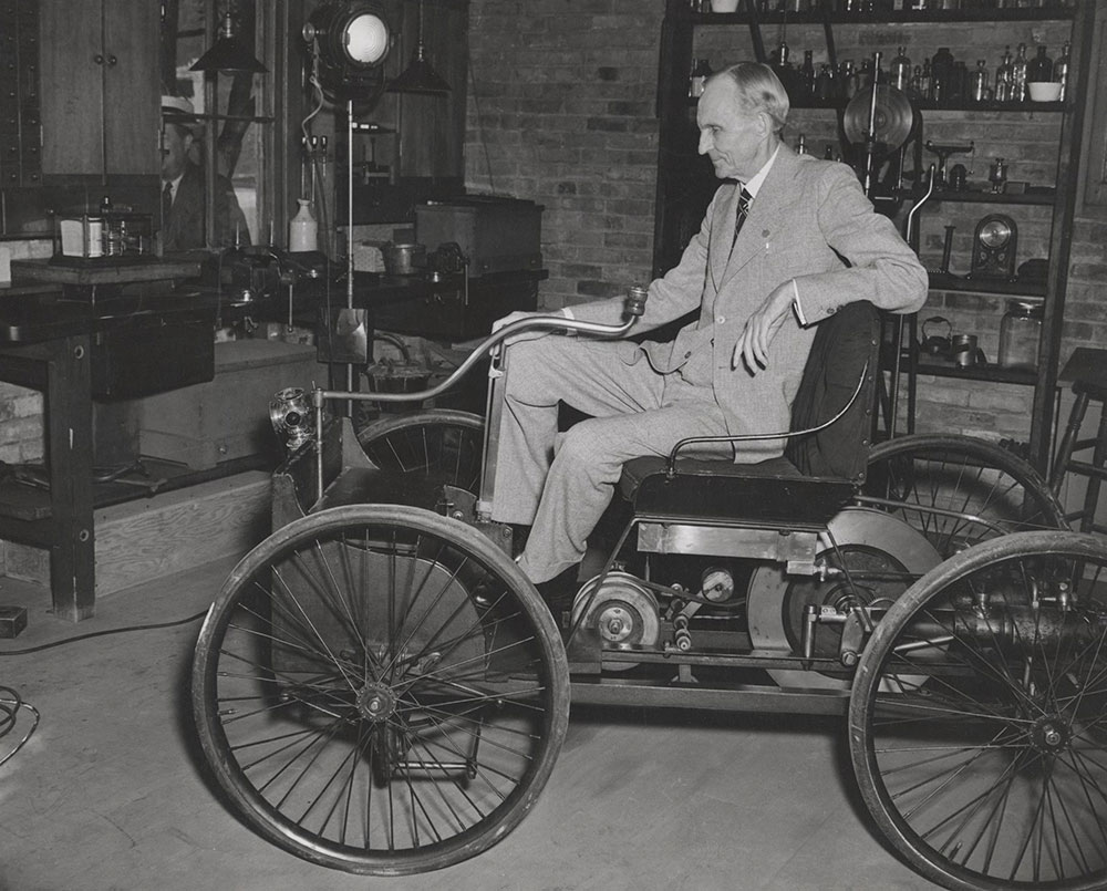 Henry Ford sitting in the Quadricycle, in a replica of the Bagely Avenue workshop