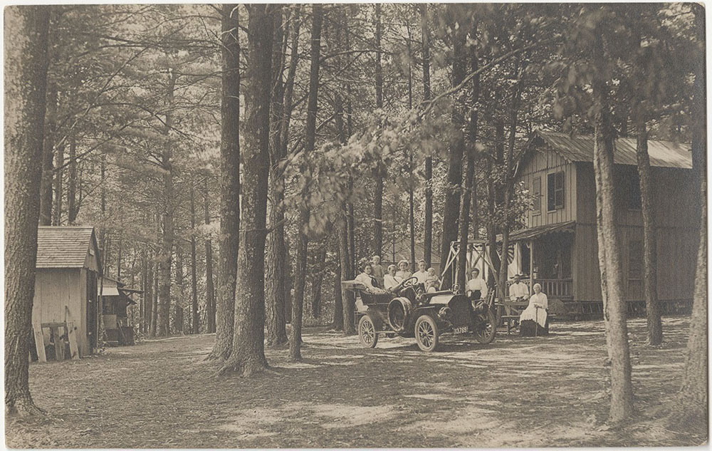 People in a Car in front of Cabin in the Woods